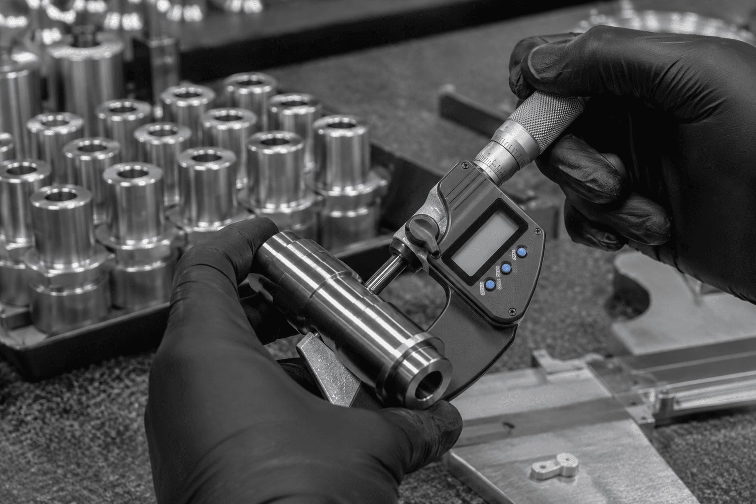 Micrometer measuring steel shaft in CNC workshop